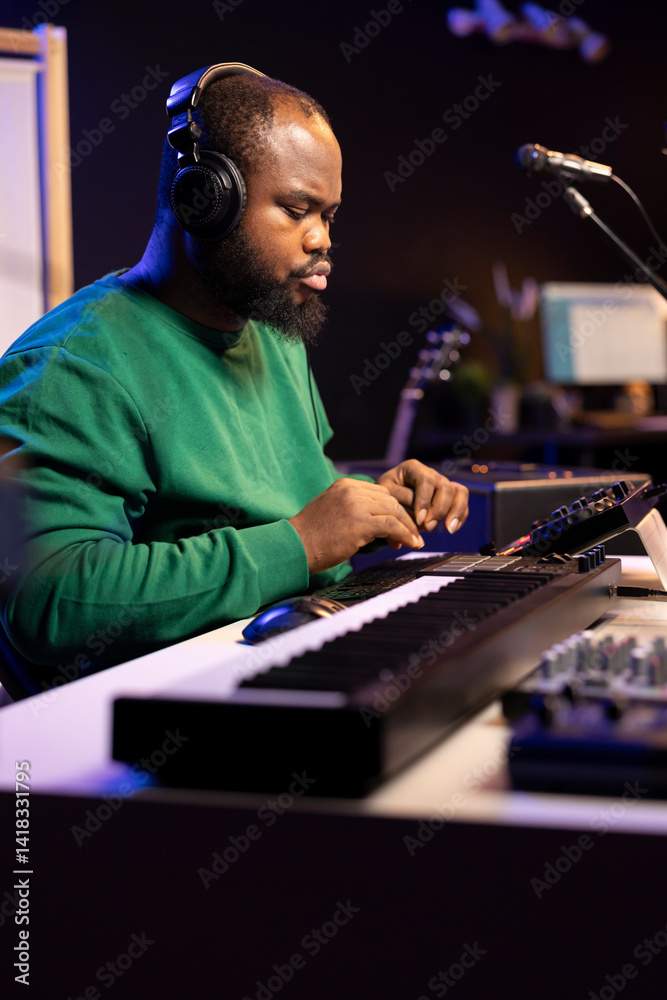 Poster Music technician with headset mixing and mastering his audio recordings, operating on a console in home studio. Musician producer creating new tunes with sound effects in post production.