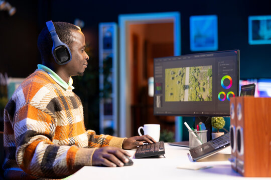 Videographer expert adjusting movie clips on computer at his home, working with color wheel and grading to add visual effects. African american editor making fx montage for video post production.