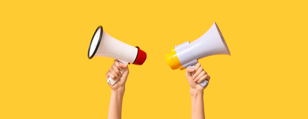 Hands holding megaphones on yellow background