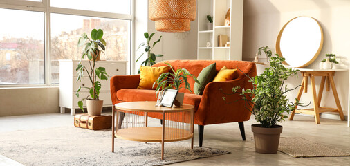 Interior of stylish living room with sofa, houseplants, table and mirror