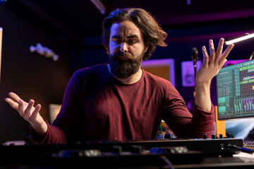 Musician feeling clueless and uncertain while he plays piano notes, trying new midi controller combinations to compose a song. Artist shrugging and being unsure about his song verses.