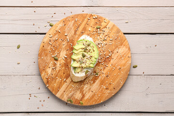 Board of tasty bruschetta with avocado on light wooden background
