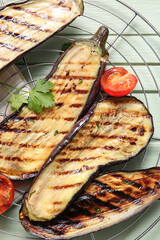 Cooling rack with delicious grilled eggplants and tomatoes on wooden background, closeup
