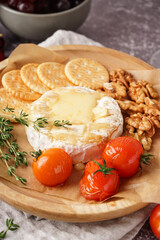 Plate of tasty baked Camembert cheese on grey background