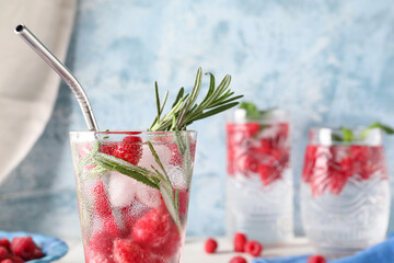 Glass of fresh raspberry lemonade with rosemary on blue background, closeup