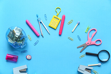 Frame made of different stationery and piggy bank with money on blue background