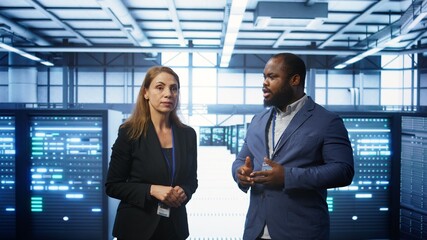 Fototapeta premium Team of admins in high tech data center looking at hologram visualization. Engineer and coworker working on securing serves using AR tech, preventing hacker attacks, camera B