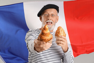 Senior man with tasty croissants against flag of France