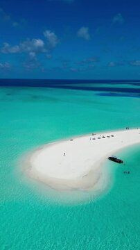 Stunning drone view showing people enjoying the sun-kissed sandbank in the Maldives
