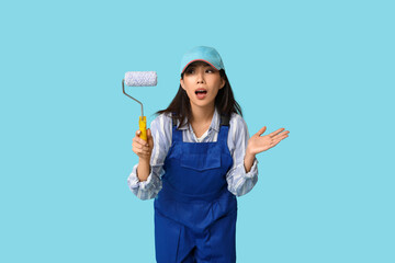Female Asian shocked painter with roller on blue background