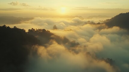 Obraz premium Golden sunrise over misty mountains with clouds, creating a serene landscape.