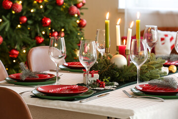 Festive table serving with burning candles, wine glasses and Christmas decorations, closeup