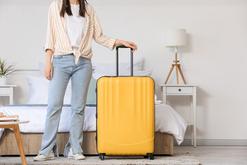 Woman with suitcase in light hotel room