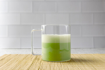 Matcha latte sitting on a bamboo mat in a modern kitchen