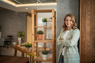 Confident entrepreneur smiling in modern office with arms crossed