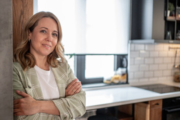 Confident businesswoman smiling with arms crossed in modern kitchen