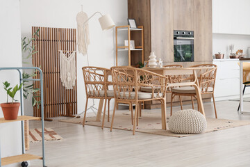 Wicker chairs, table and folding screen in interior of stylish dining room
