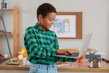 Cute little architect with laptop at home
