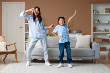 Beautiful young woman and her little son listening to music and dancing at home