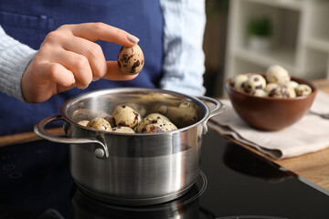 Woman boiling quail eggs on electric stove in kitchen, closeup