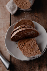 Freshly baked rye bread in a plate on wooden background.