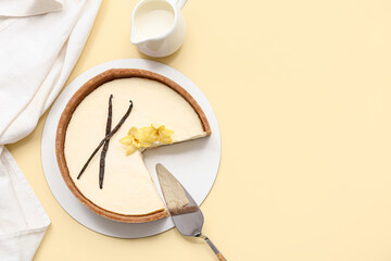 Cut sweet vanilla cheesecake with vanilla flowers and sticks on yellow background