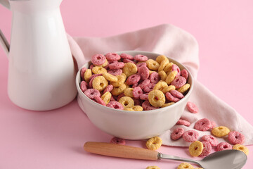Bowl with color cereal rings on pink background, closeup