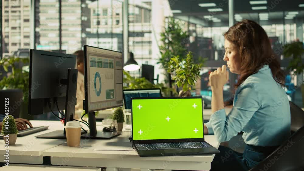 Poster green screen laptop on office desk next to employee editing documents on computer. mockup notebook n