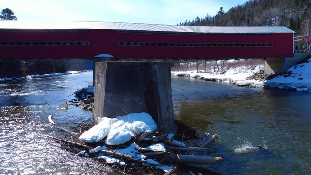 View of the central pillar holding the wooden structure of a historic covered bridge and its concrete structure to protect it from upstream debris. Matapedia River, Routhierville Bridge, Quebec.