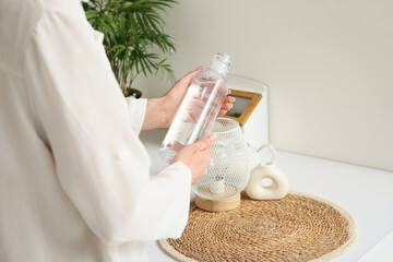 Woman holding bottle of water with time stamps in kitchen, closeup