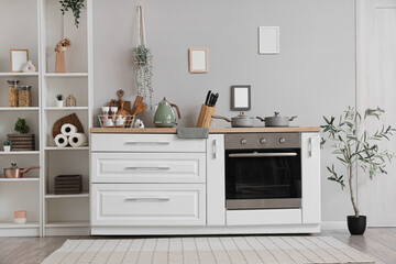Interior of stylish kitchen with white counters, oven and different utensils