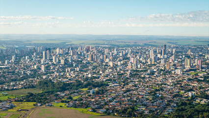 Aerial close-up of Cascavel, Paraná, Brazil, showing a dense urban skyline surrounded by countryside and fields under a clear sky.