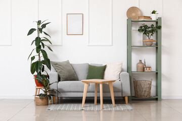 Interior of stylish living room with grey sofa, coffee table and shelving unit