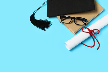 Mortar board with diploma, book and eyeglasses on blue background, closeup