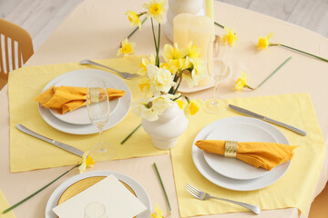 Elegant table setting with beautiful narcissus flowers and folded napkins on plates