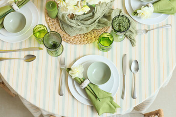 Elegant table setting with beautiful narcissus flowers, glasses and candles