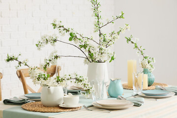 Elegant table setting with plates, glasses and blooming tree branches