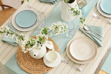 Elegant table setting with plates, glasses and blooming tree branches, top view