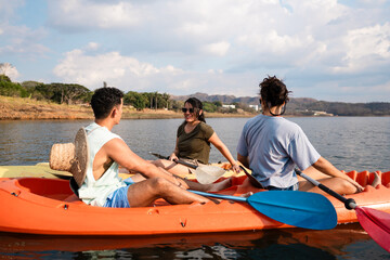 Group of young adults kayaking on a calm lake, enjoying an outdoor adventure on a sunny day surrounded by nature