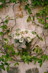 Bridal bouquet in branches of green ivy on an old stone building
