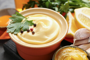 Delicious mayonnaise sauce in bowl and ingredients on grey table, closeup