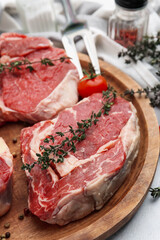 Pieces of raw beef and spices on light grey table, closeup
