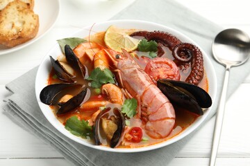 Delicious seafood soup served on white wooden table, closeup