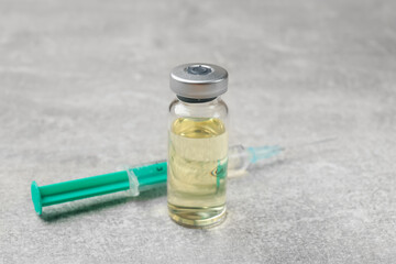 Hepatitis vaccine in glass vial and syringe on grey table, closeup