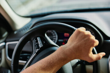 Naklejka premium Close up of a hand gripping a steering wheel inside a car cabin, indicating motion and driving experience
