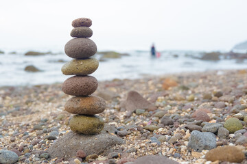 A carefully balanced stack of smooth pebbles on a rocky beach, symbolizing harmony, mindfulness, and stability.