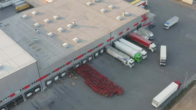 Aerial Drone View of Modern Logistics Warehouse with Many Semi Trucks Loading and Unloading at Ramps