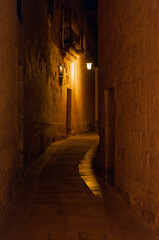 A narrow alleyway with a light on the wall