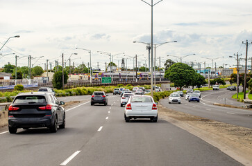 A road running parallel to a railway line, with cars and vehicles traveling on multiple lanes. Train infrastructure alongside the roadway in Geelong, Australia