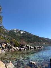 Smooth rocks emerge from Lake Tahoe’s crystal-clear shoreline, reflecting the lake’s natural...